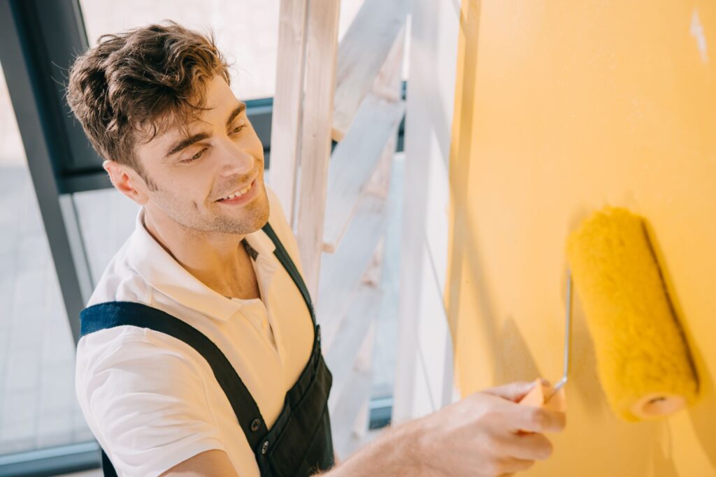 handsome-young-painter-smiling-while-painting-wall-2023-11-27-05-05-35-utc.jpg