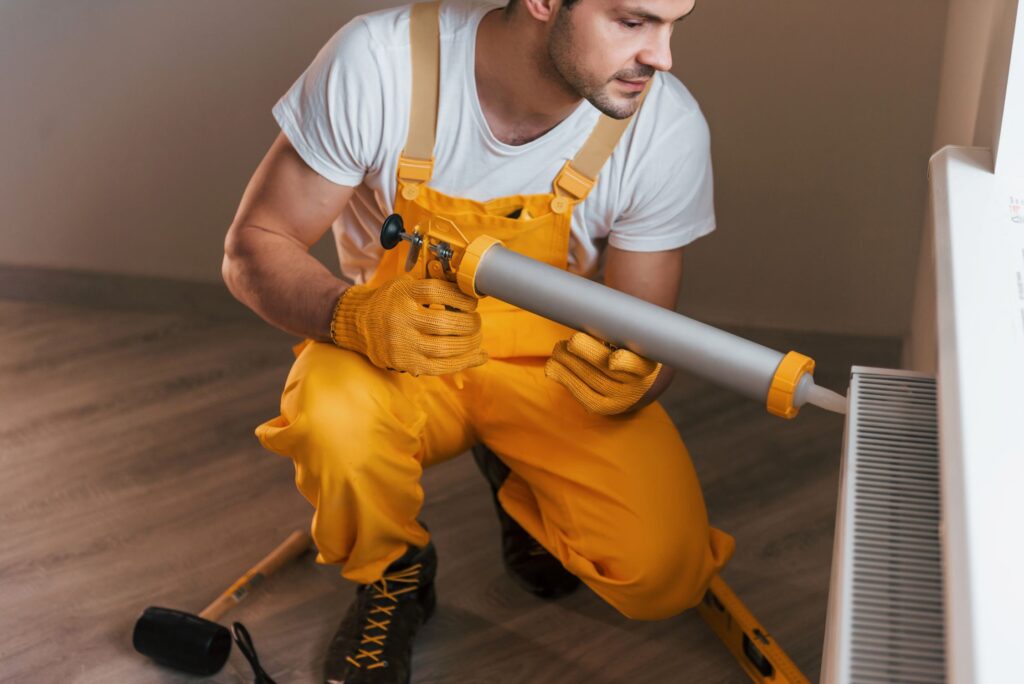 handyman-in-yellow-uniform-works-indoors-with-heat-2023-11-27-05-30-32-utc.jpg